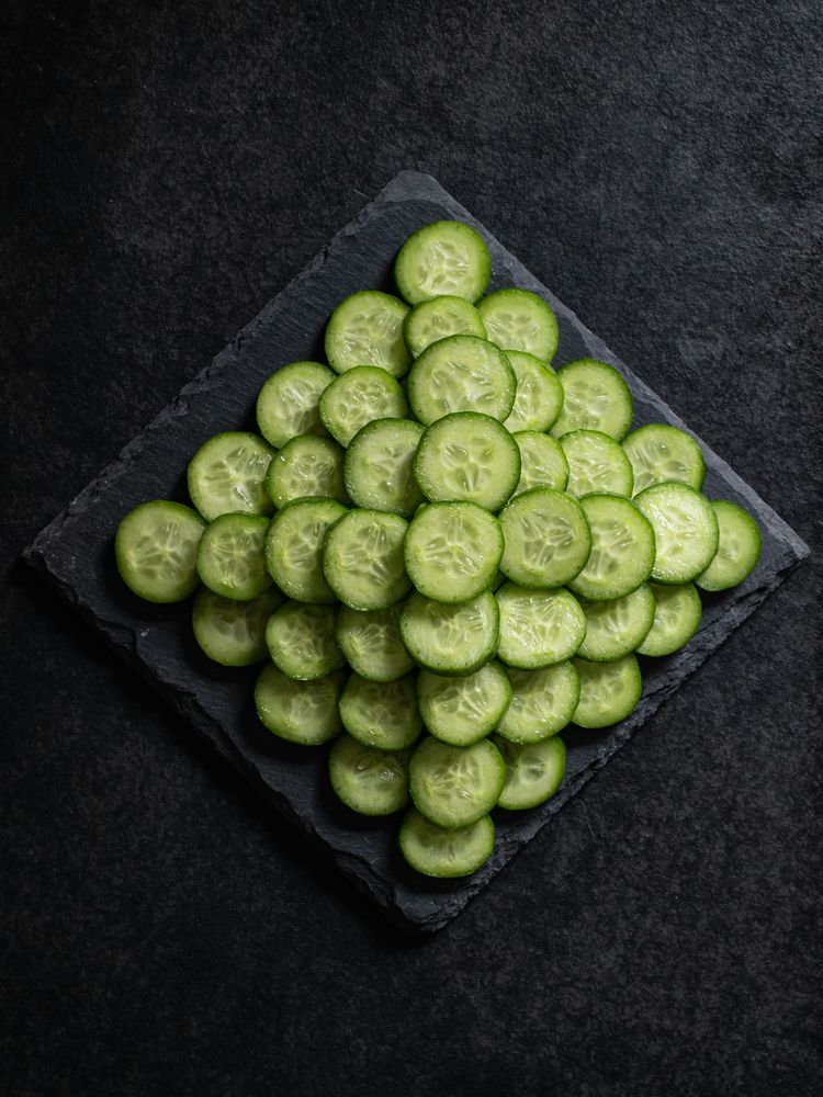 Sliced cucumber arranged on a dark slate surface