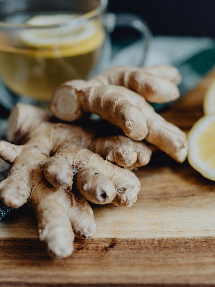 Fresh ginger root beside sliced lemon and tea
