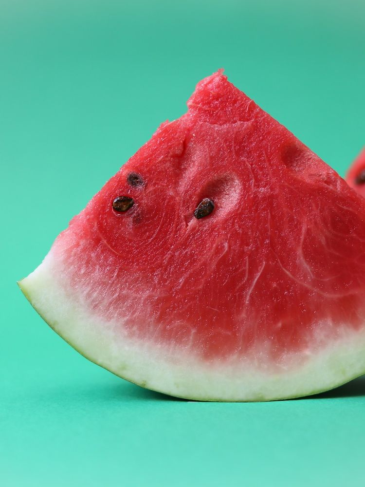 A watermelon wedge with seeds visible against a green background